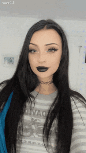 a woman wearing a choker and a striped shirt with a motorcycle on it looks at the camera
