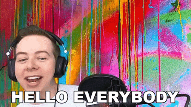 a man wearing headphones and a microphone is standing in front of a colorful wall .