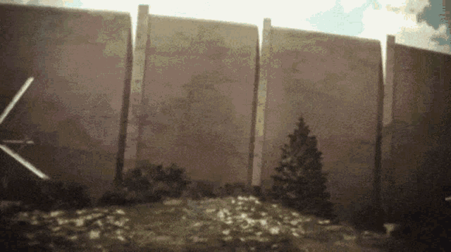 a very tall wall with a few trees in front of it