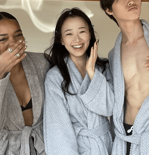 two women and a man in bathrobes are posing for a photo