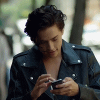 a man in a black leather jacket is looking at his cell phone