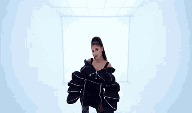 ariana grande is wearing a black tank top and a black and white jacket .