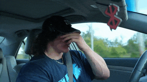 a man wearing a hat that says nyc on it is covering his face in a car