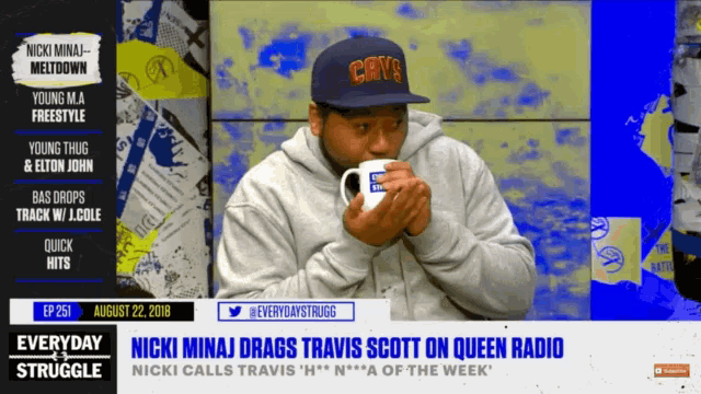 a man wearing a cavs hat is holding a coffee mug