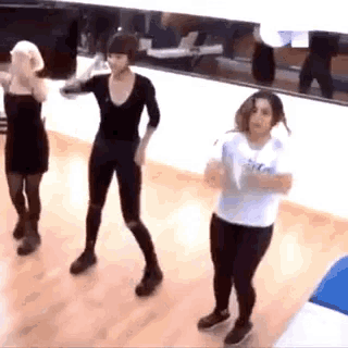 three women are dancing in front of a mirror and one of them is wearing a white shirt that says ' ice '
