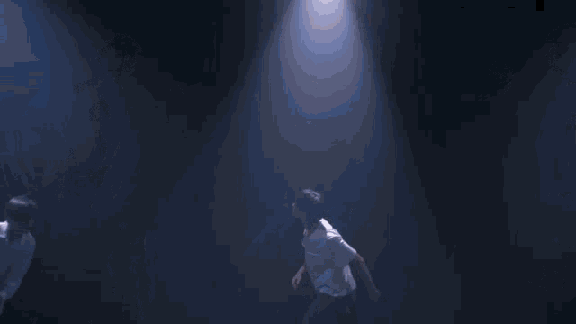 a group of young men are standing in a dark room with their arms outstretched