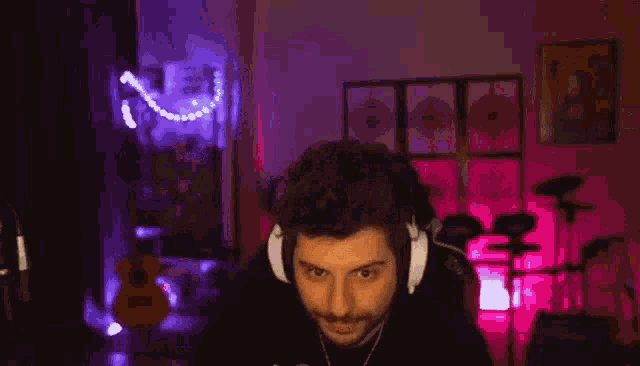a man wearing headphones is giving a thumbs up in front of a microphone .