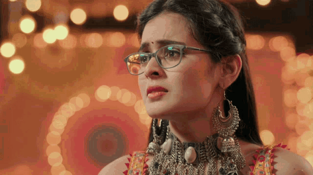 a woman wearing glasses and earrings looks sad
