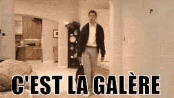 a man is walking through a living room with the words c ' est la galere written on the bottom