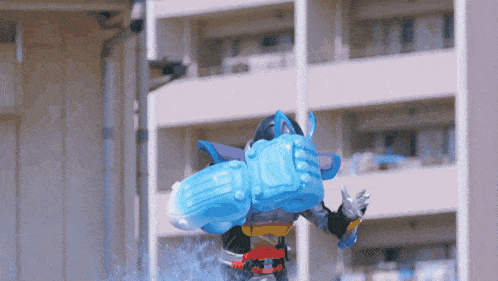 a cartoon character with a huge blue item on his back is standing in front of a building
