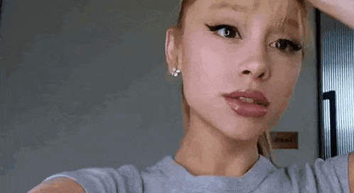 a close up of a woman taking a selfie with her hand on her forehead .