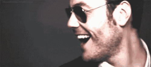 a close up of a man wearing sunglasses and a white shirt .