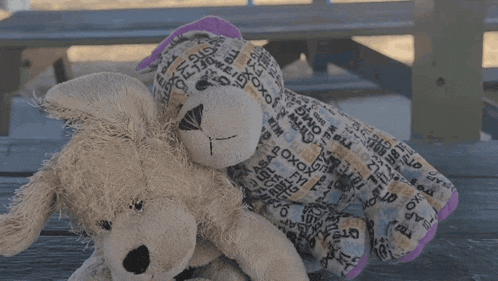 two stuffed animals are laying on a picnic table one of which has the word tpms on it