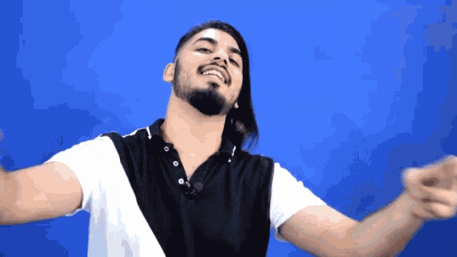 a man with a beard and long hair is smiling and pointing at the camera