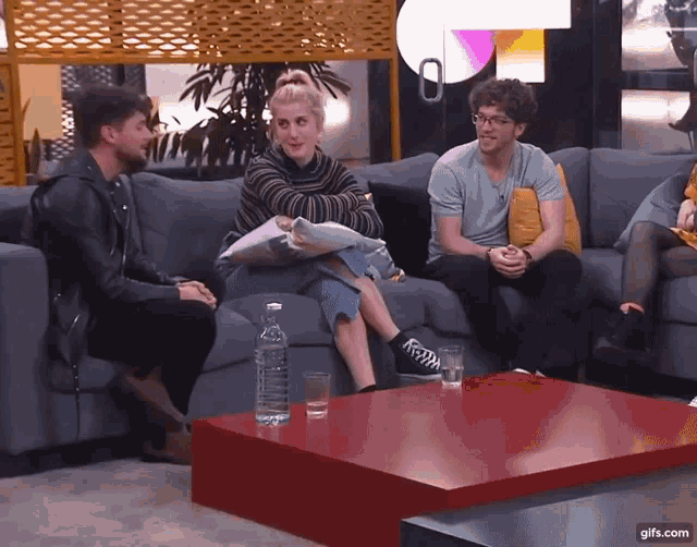 a group of people are sitting on a couch with a red table