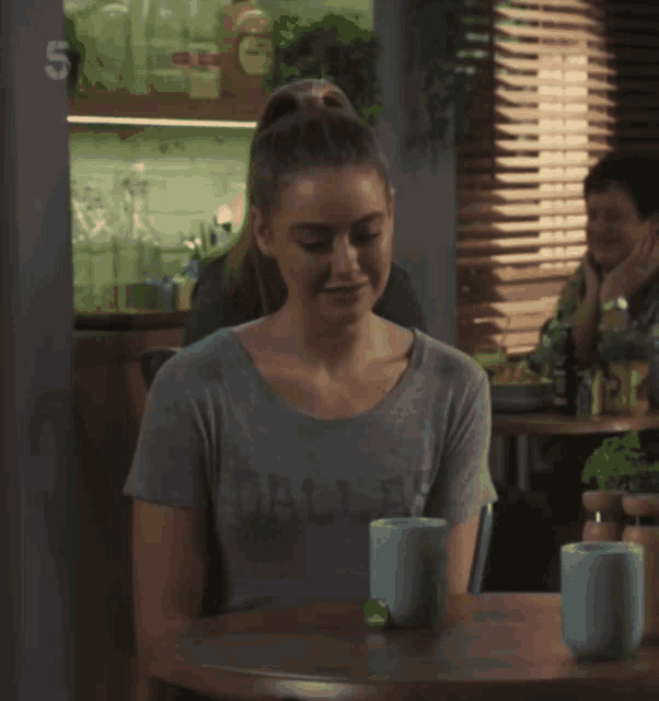 a woman in a dallas shirt sits at a table with two cups
