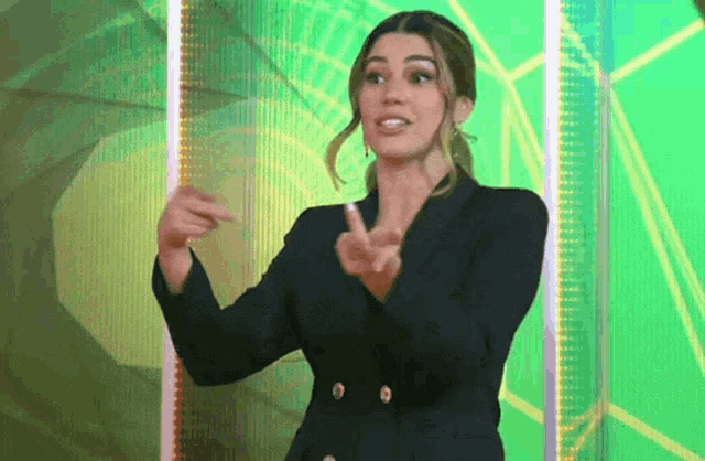 a woman in a black jacket is pointing her finger at something
