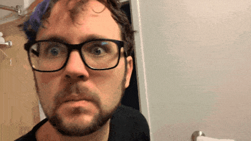 a man with glasses and a beard looks surprised