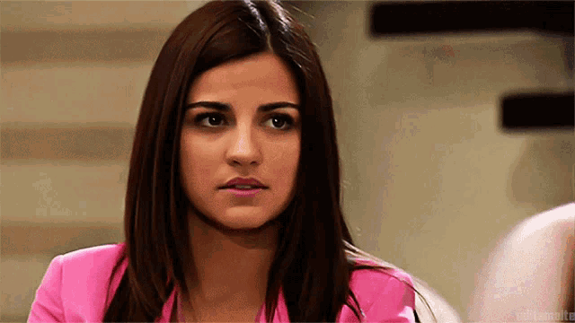 a close up of a woman 's face with a pink shirt on