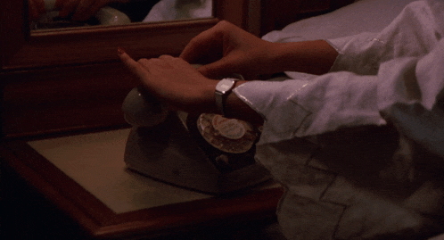 a woman wearing a white shirt is sitting on a bed with her hands outstretched