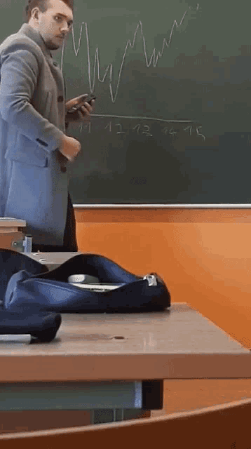 a man is standing in front of a blackboard with the number 11 12 13 14 15 written on it