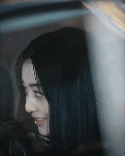 a woman with long black hair is smiling in a car