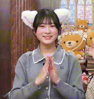 a girl wearing a cat ear headband is smiling and clapping her hands .
