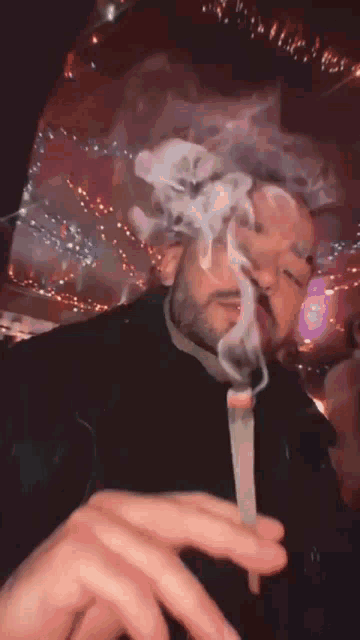 a man is smoking a cigarette in a dark room