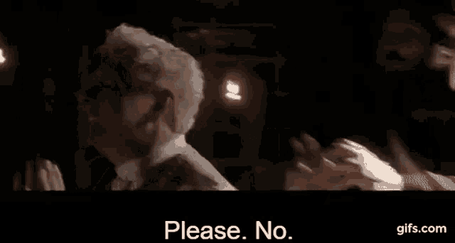 a man in a suit and tie is talking to another man in a dark room and says `` please no '' .
