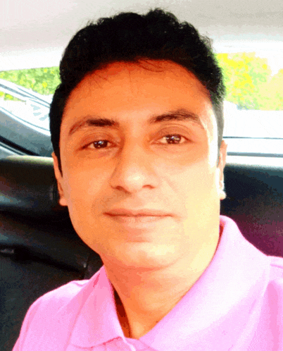 a man wearing a pink shirt is sitting in the back seat of a car