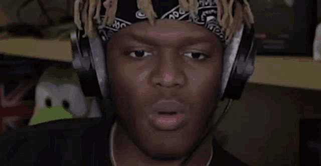 a man wearing headphones and a bandana is making a face .