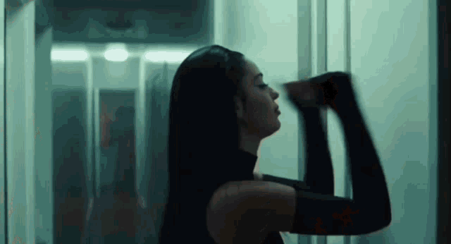 a woman in a black dress is standing in a hallway with her arms outstretched .