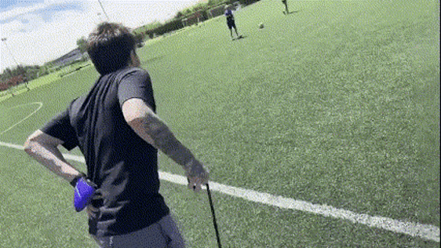 a man is standing on a soccer field holding a blue frisbee