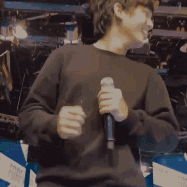 a man in a black sweater is holding a microphone in his hand