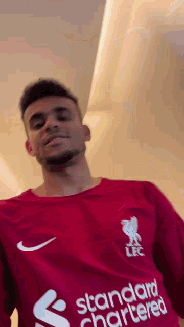 a man wearing a red shirt with the word standard chartered on it