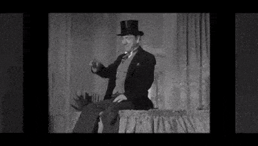 a man in a top hat is sitting on a bed