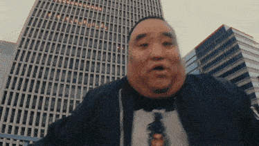 a man stands in front of a tall building with a surprised look on his face ..