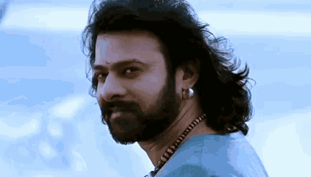 a man with long hair and a beard wearing a blue shirt