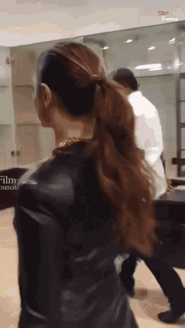 a woman in a black leather jacket is walking in front of a glass wall with the words film council written on it