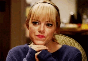 a woman with blonde hair and bangs is sitting in a chair with her hands on her chin .