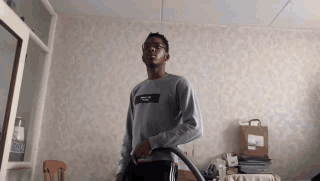 a man wearing a sweater that says ' where the fuck ' on it is holding a vacuum cleaner