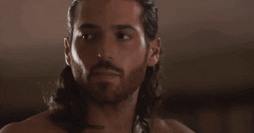 a man with long hair and a beard is looking at the camera
