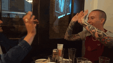 a man with a tattoo on his arm gives a high five