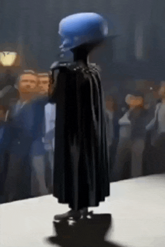 a cartoon character wearing a cape is standing in front of a crowd .