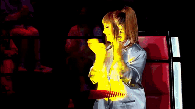 a woman applauds in front of a banner for the voice portugal