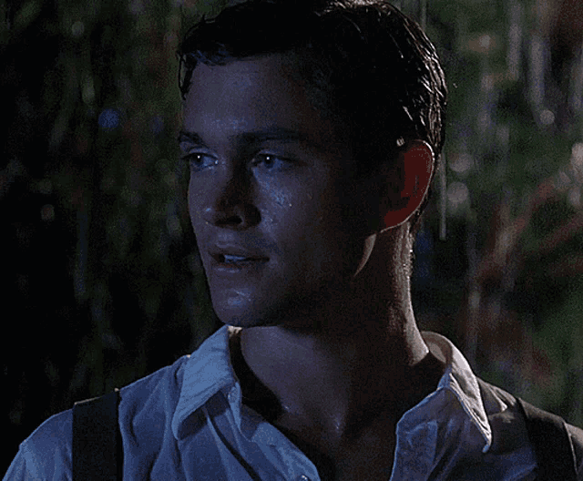 a man in a white shirt is standing in the rain