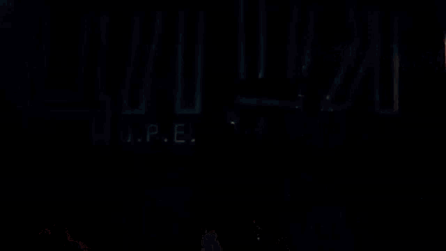 a woman in a red dress is holding a gun and looking at a man in a dark room .