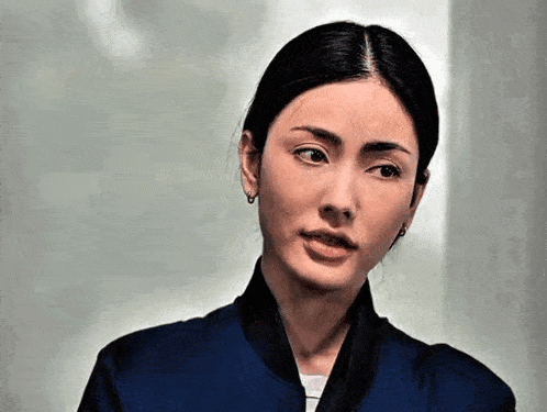 a woman wearing a blue jacket and black scarf looks at the camera