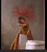 a stuffed animal wearing a white apron and a red feathered hat