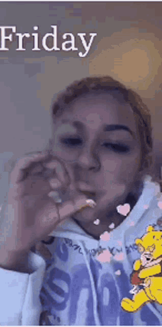 a woman in a winnie the pooh hoodie is smoking a cigarette on friday .